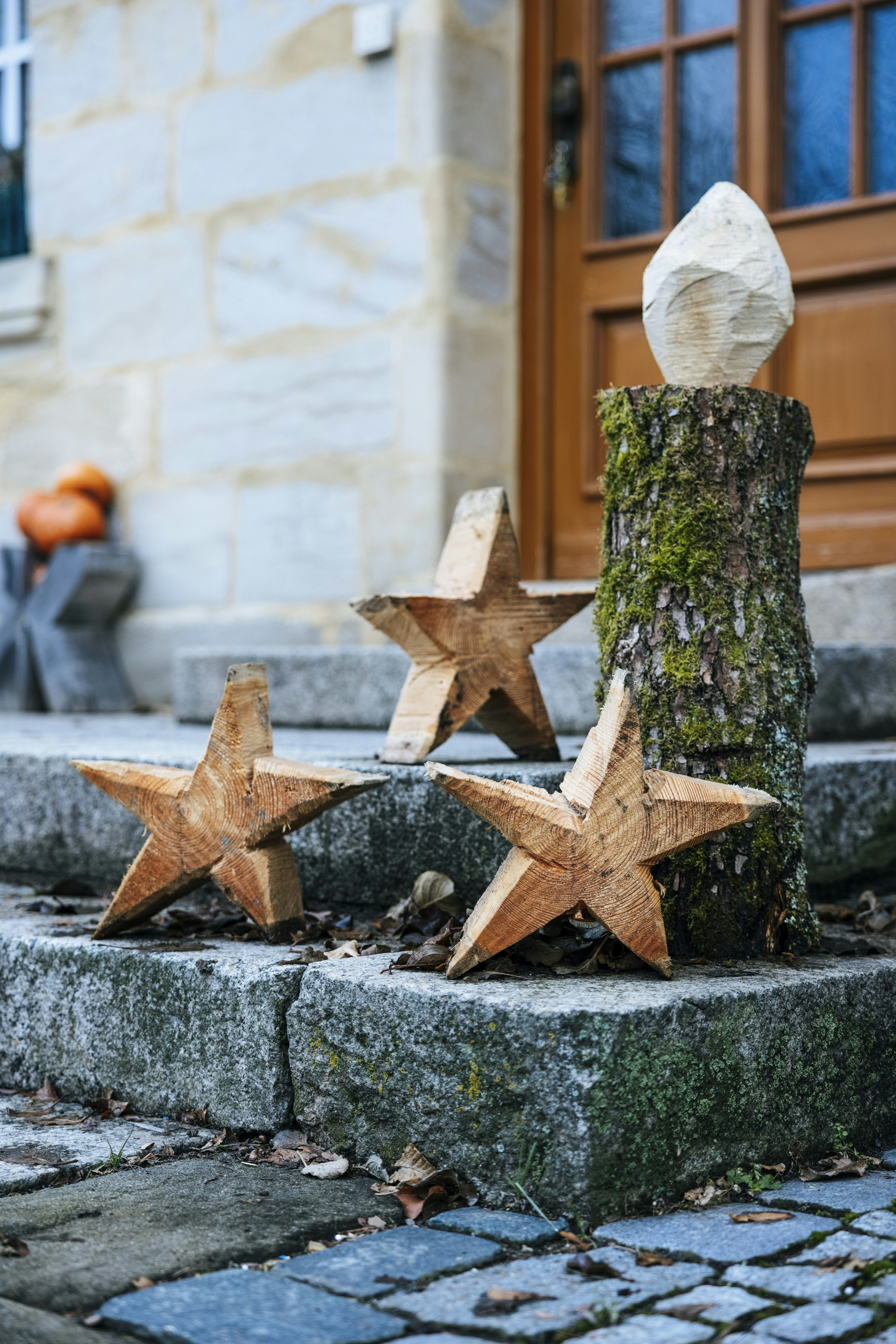 three wooden stars are placed next to a tree stump