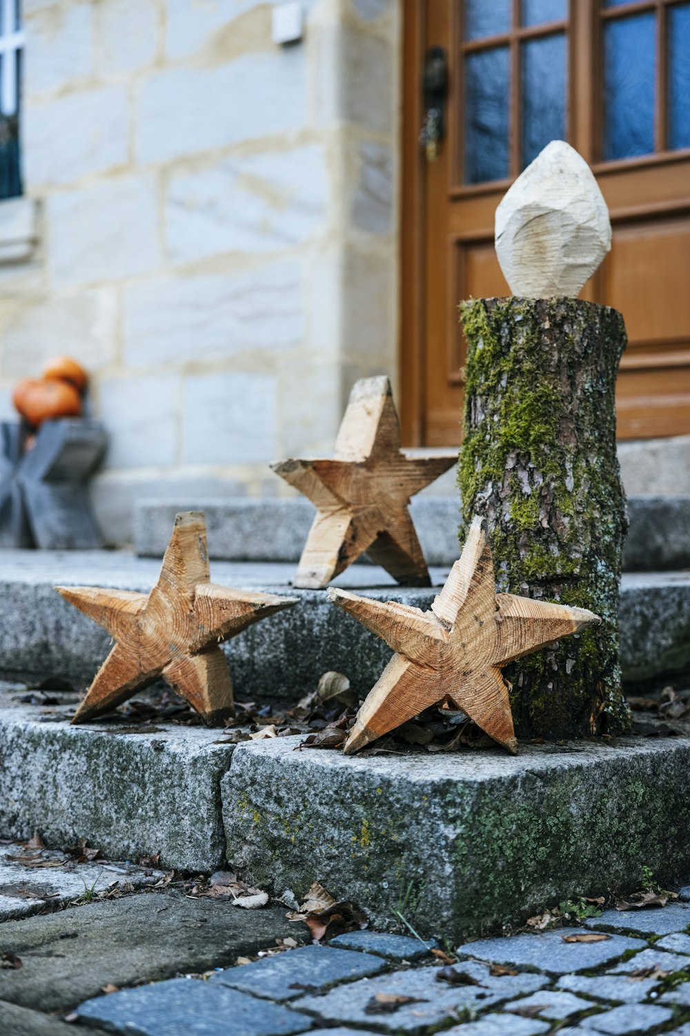 three wooden stars are placed next to a tree stump