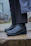 Close-up of a pair of sleek shoecovers protecting stylish leather shoes on a rainy city sidewalk.