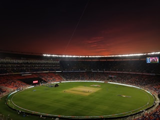 a baseball stadium with a full field and a red sky