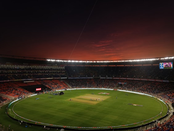a baseball stadium with a full field and a red sky