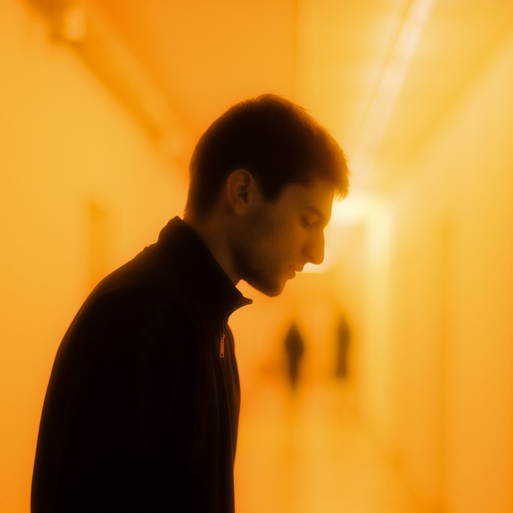 a man standing in a hallway looking down at his cell phone