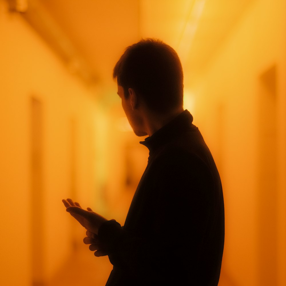 a man standing in a hallway using a cell phone