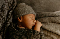 A newborn peacefully sleeping wrapped in a cozy blanket embroidered with the foundation's logo.