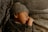 A newborn baby is peacefully sleeping, wrapped in a cozy knitted blanket and wearing a matching knit hat. The texture of the knitted fabric surrounds and envelops the baby, creating a warm and comforting atmosphere.