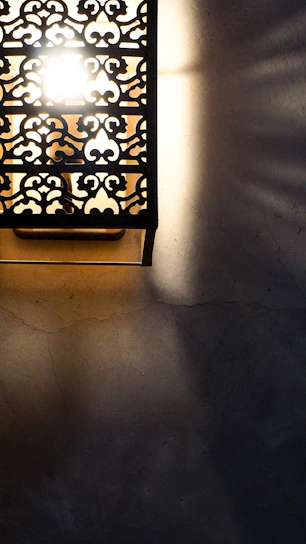 Close-up of an intricately designed metal wall sconce casting soft shadows on a textured wall