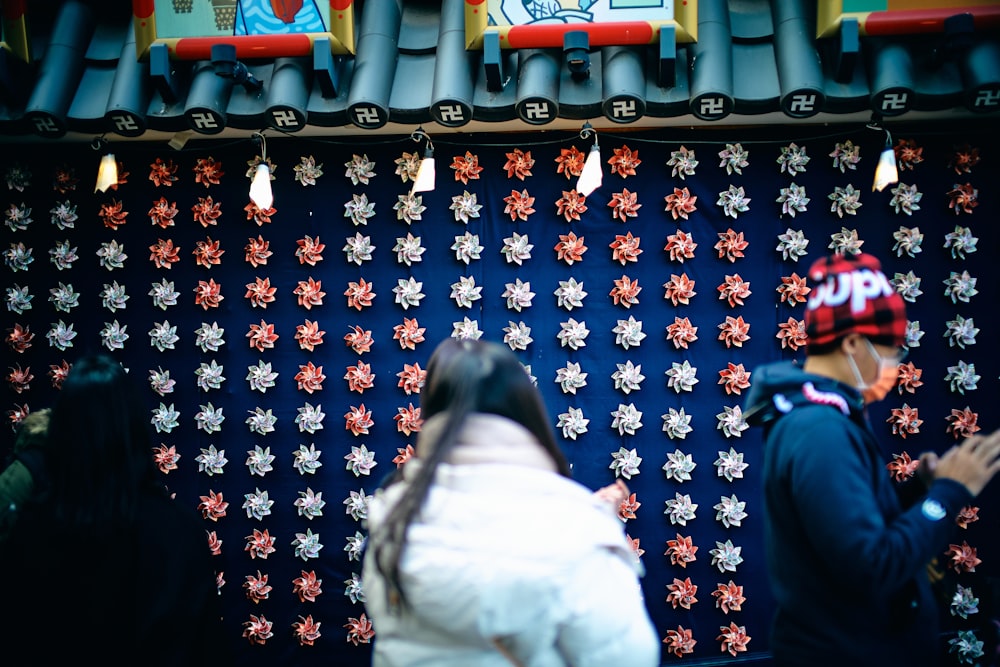 a man and a woman standing in front of a wall covered in snowflakes