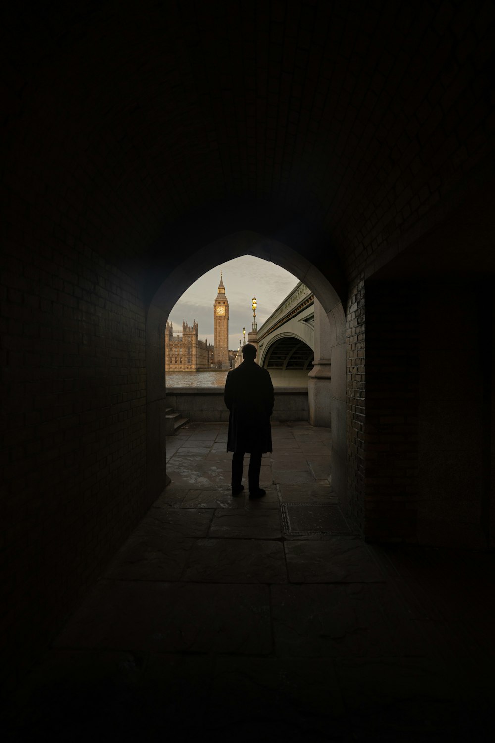 a man standing in a tunnel with a clock tower in the background