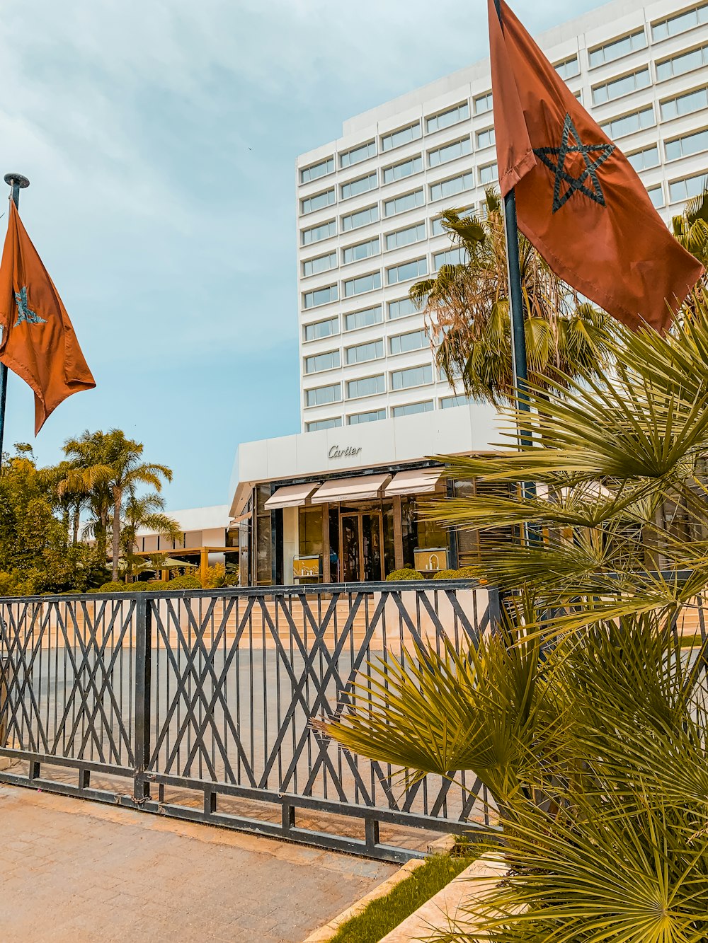 a fence with two orange flags and a building in the background