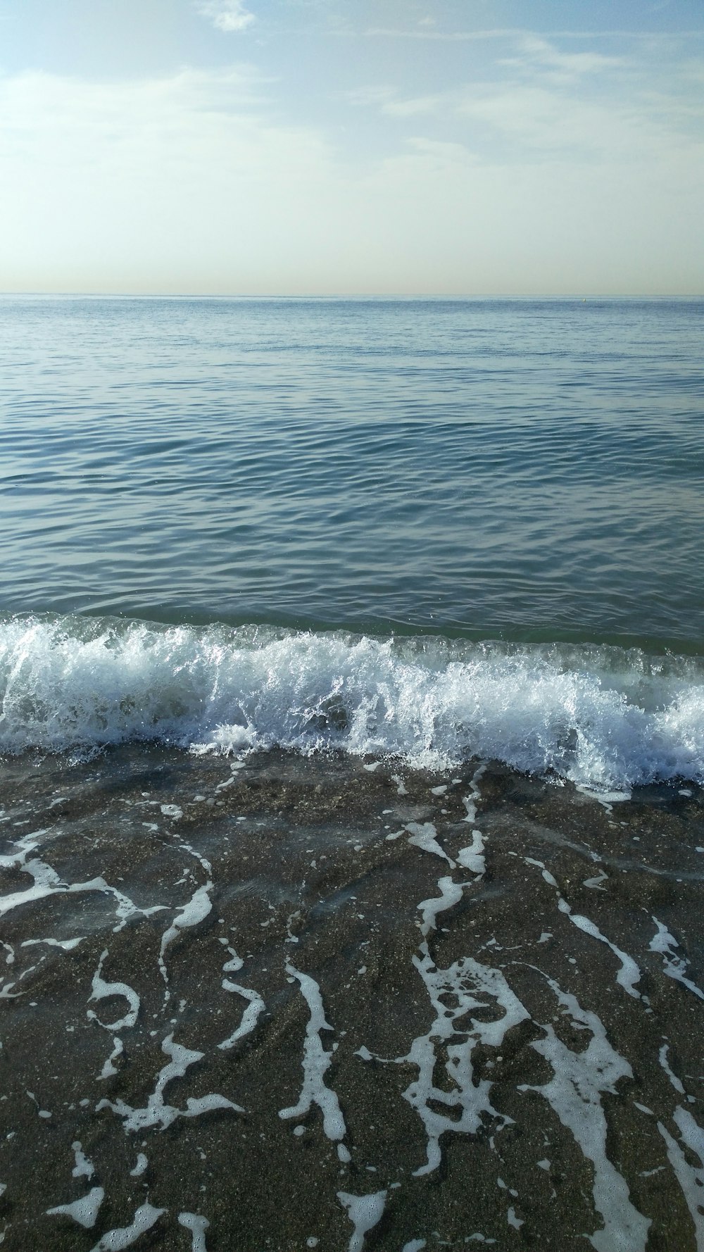 a wave rolls in on the shore of the ocean