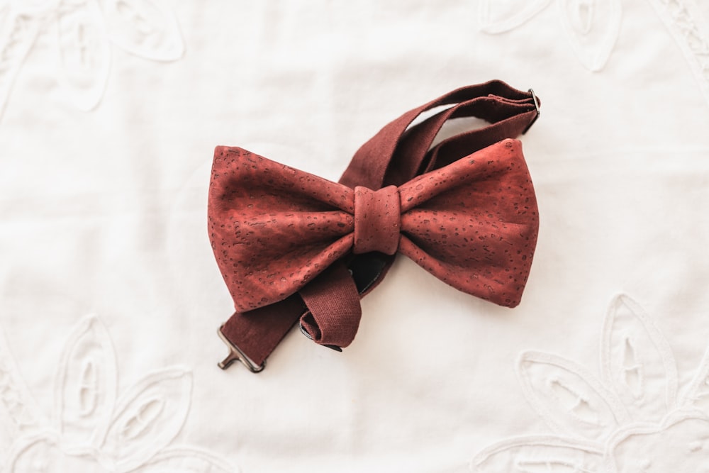 a red bow tie laying on top of a white sheet