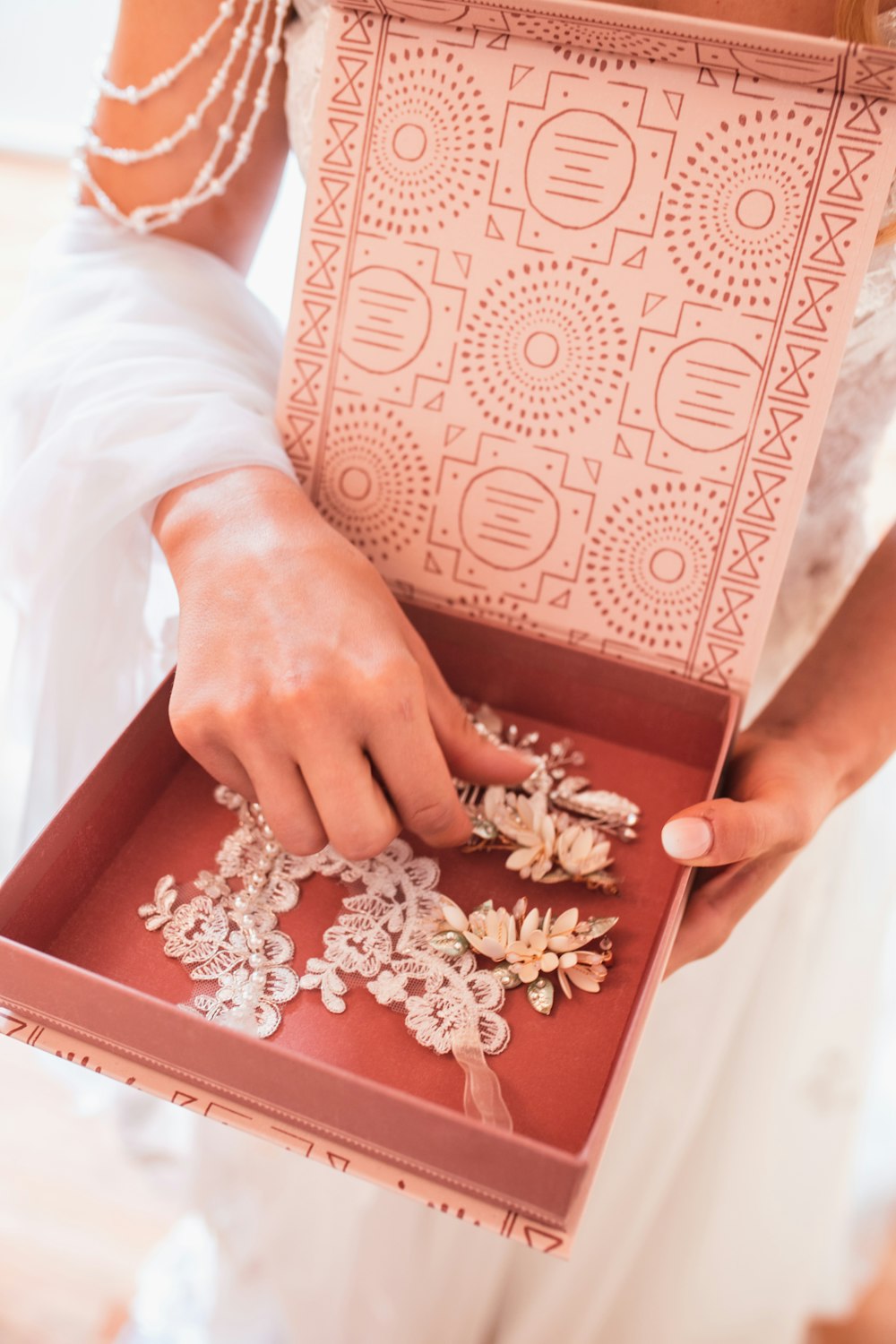 a woman holding a box with a bunch of jewelry inside of it