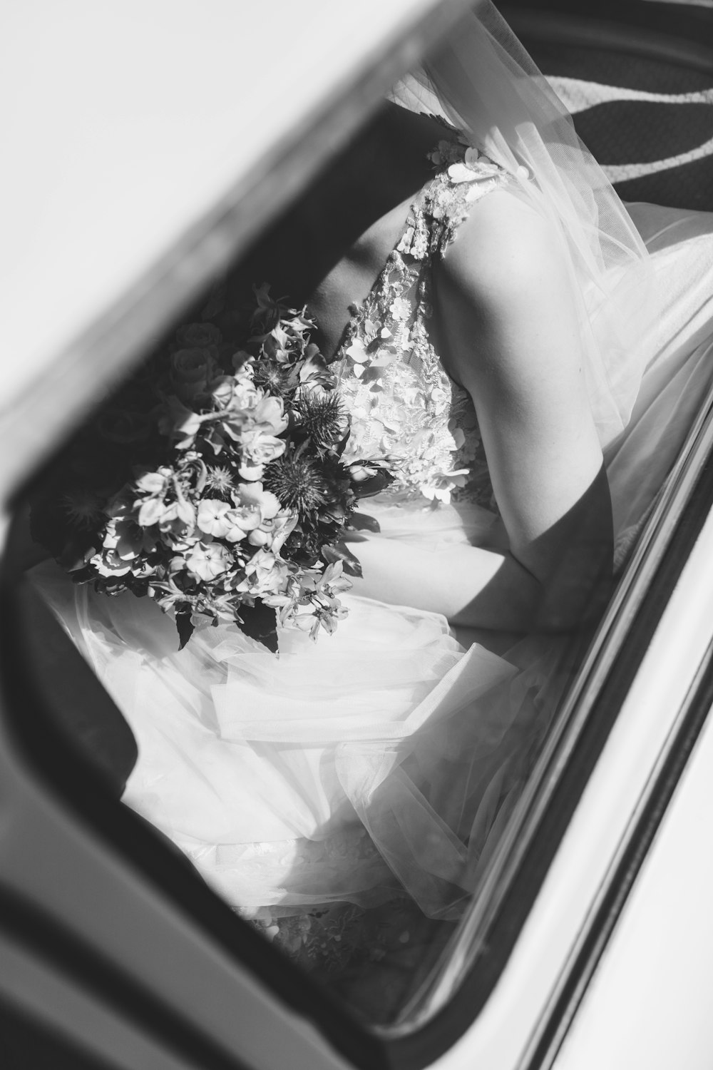 a woman in a wedding dress sitting in a car