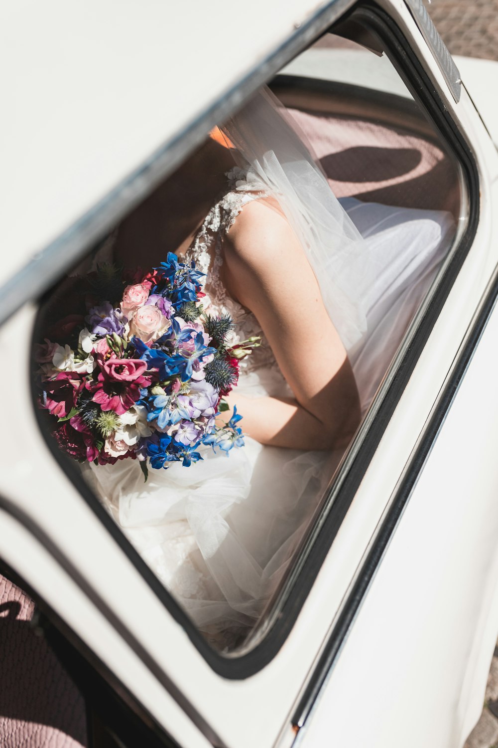 a woman in a wedding dress sitting in a car