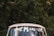 A vintage car with a 'Just Married' sign on the rear window is positioned in front of a lush, green forest background.