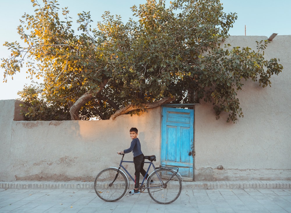 a young boy riding a bike past a blue door