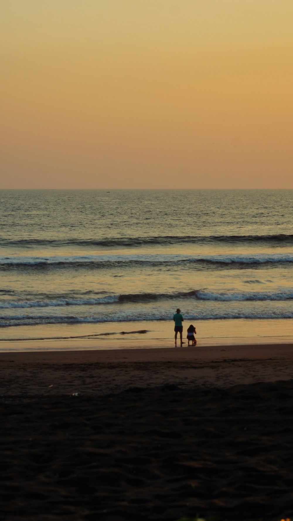 a couple of people standing on top of a sandy beach