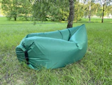 Inflatable outdoor lounger resting on a grassy hill under a clear blue sky.