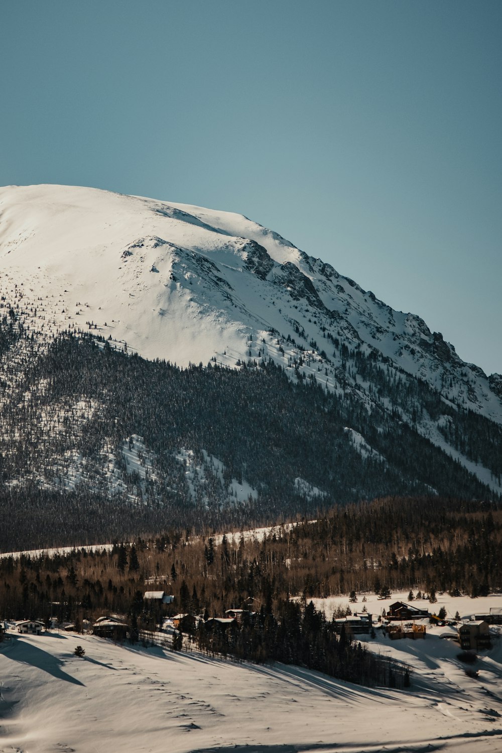 ein schneebedeckter Berg mit Bäumen an der Seite