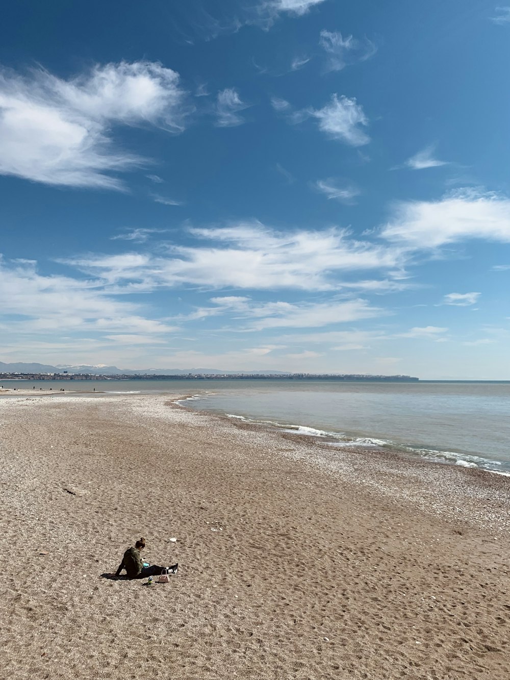 a person sitting on a beach next to the ocean