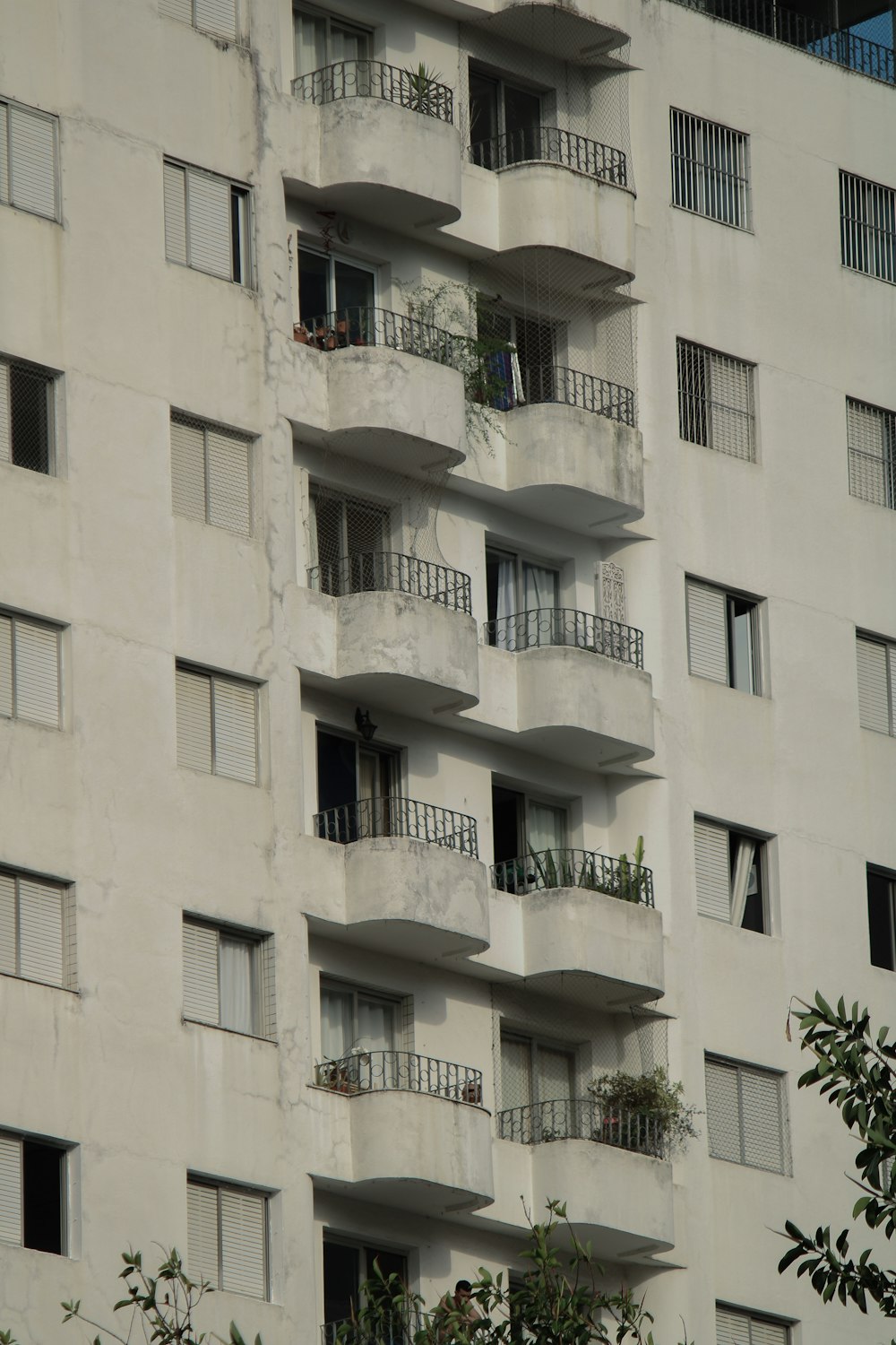 a tall building with balconies and plants on the balconies