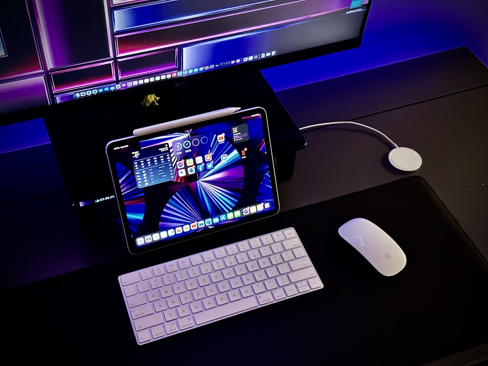 a tablet computer sitting on top of a desk next to a keyboard