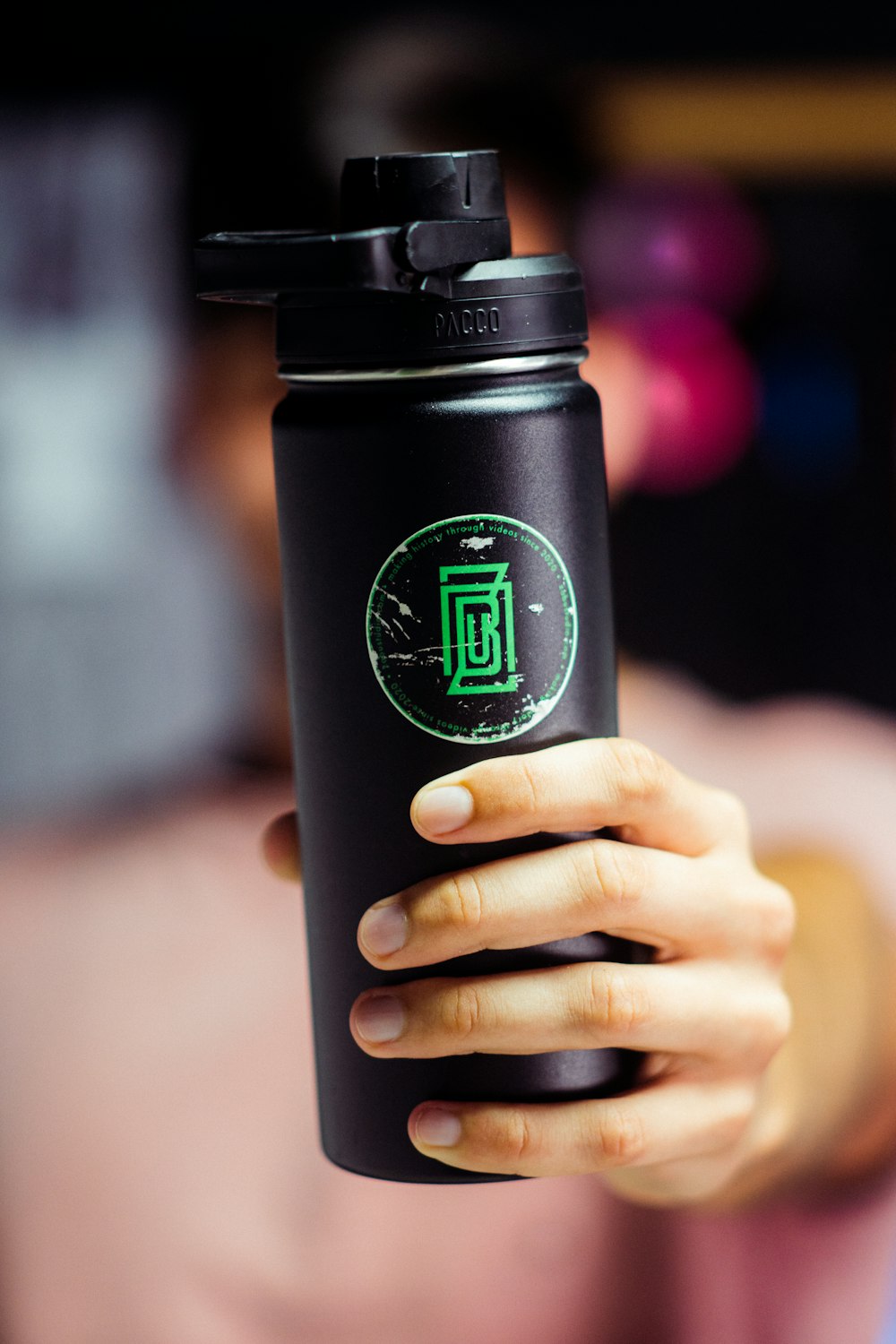 a person holding a black coffee cup with a green logo