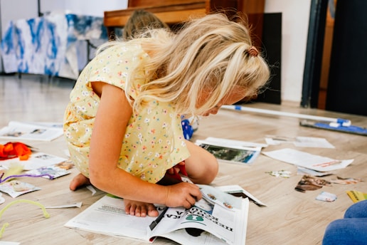 a little girl sitting on the floor looking at a book