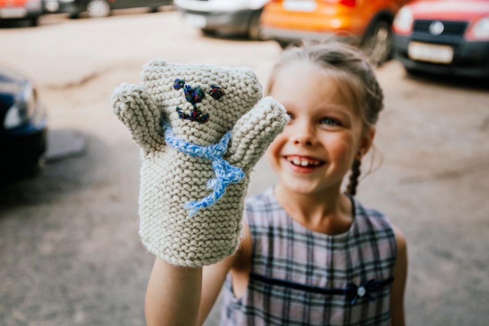 a little girl holding up a crocheted teddy bear