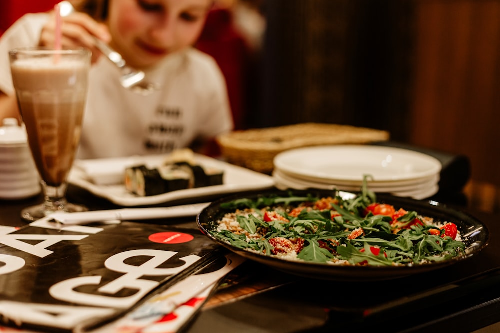 a child sitting at a table with a plate of food