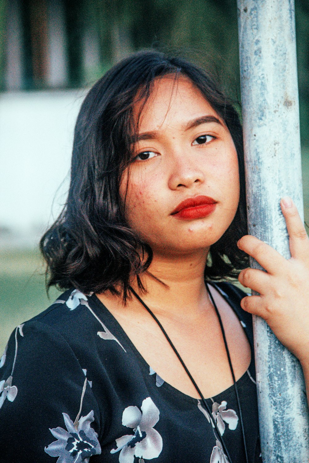 a woman leaning against a pole with her hand on the pole