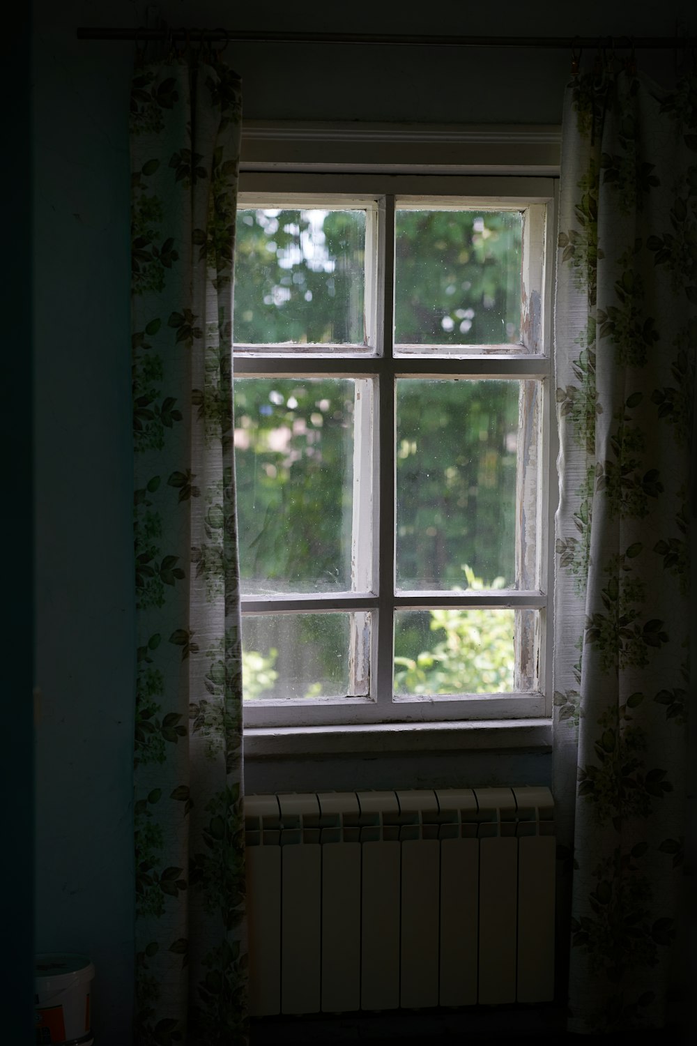 a window with curtains and a radiator in front of it