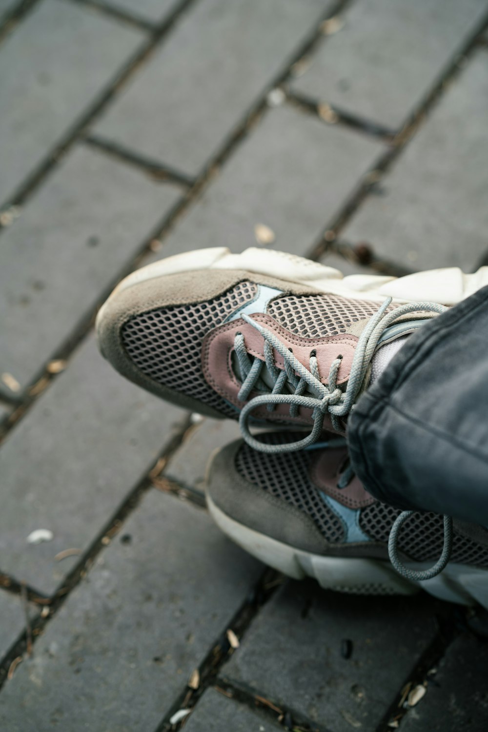 a person standing on a sidewalk with a pair of shoes