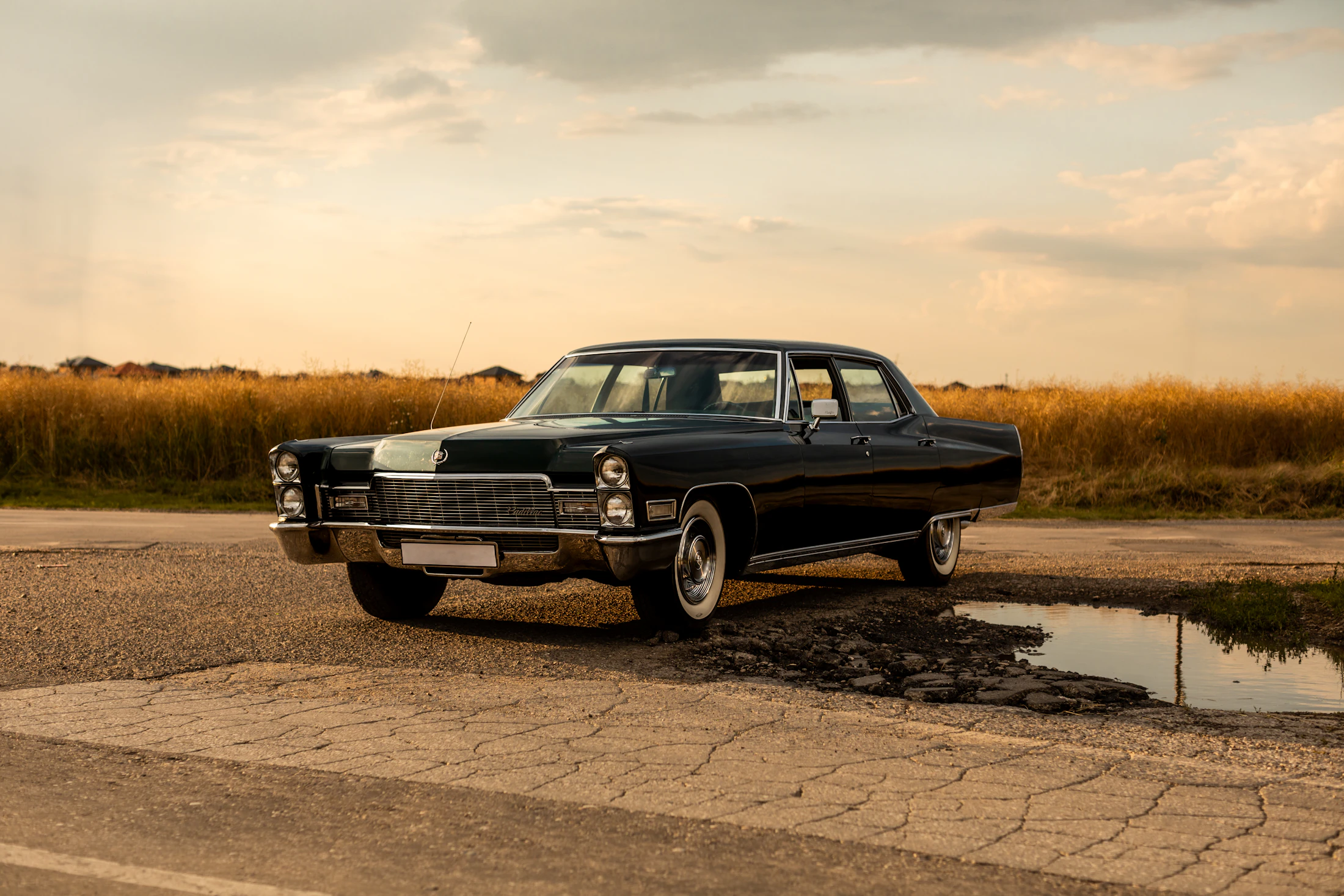 Black vintage Cadillac parked at the roadside, its long body and chrome catching the light