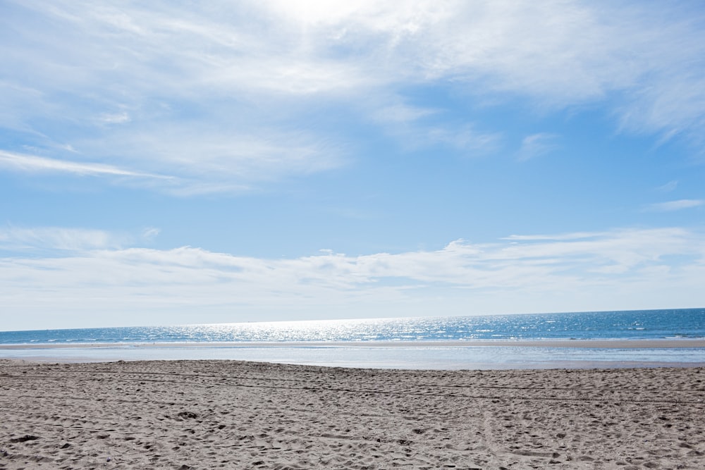 a person walking on a beach carrying a surfboard