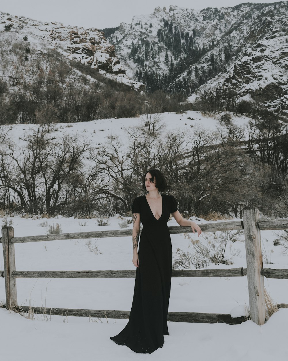 a woman in a black dress standing in the snow