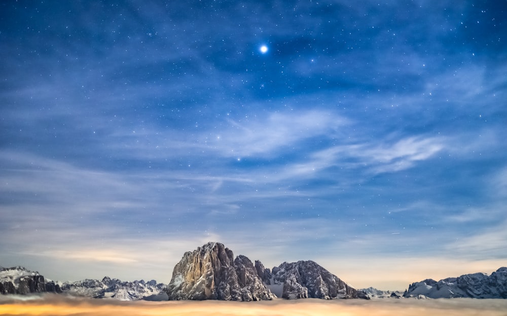 a mountain range under a blue sky with stars