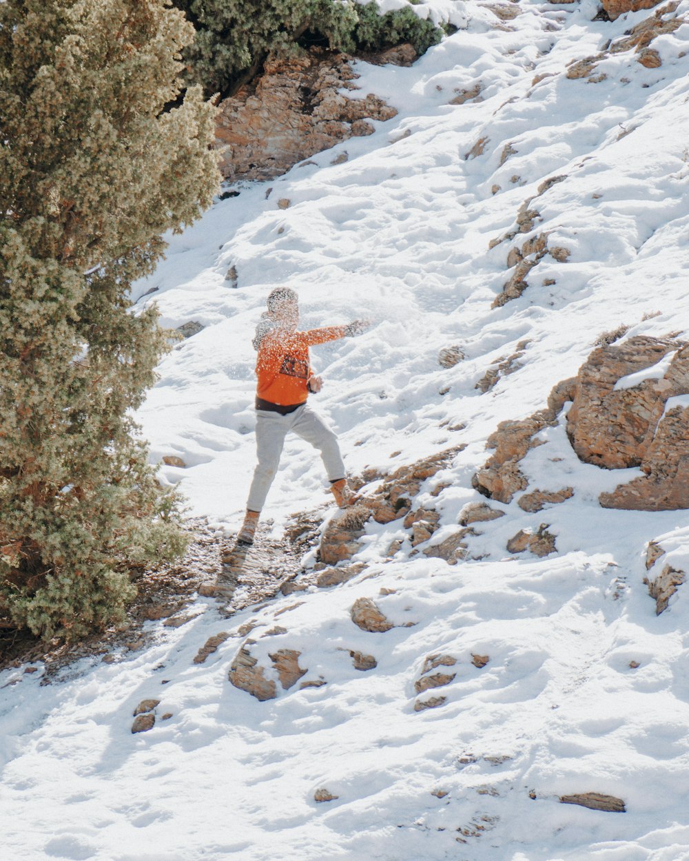 a person in an orange jacket is skiing down a snowy hill