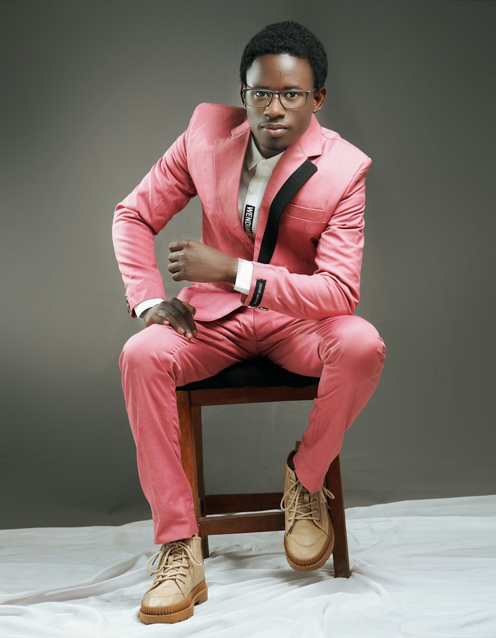 a man in a pink suit sitting on a stool