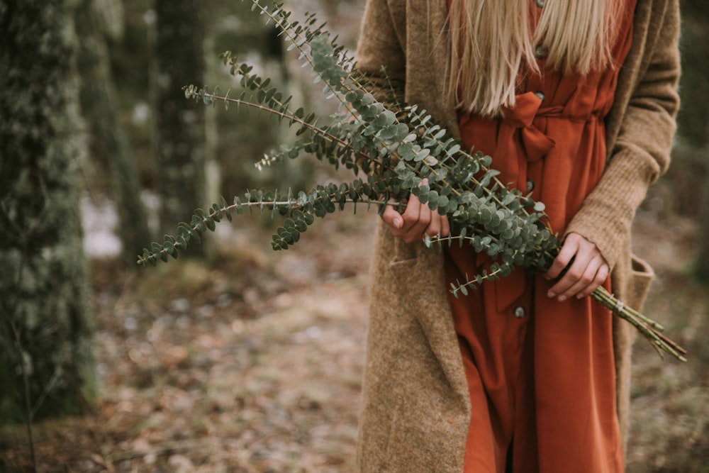 a woman in an orange dress holding a plant