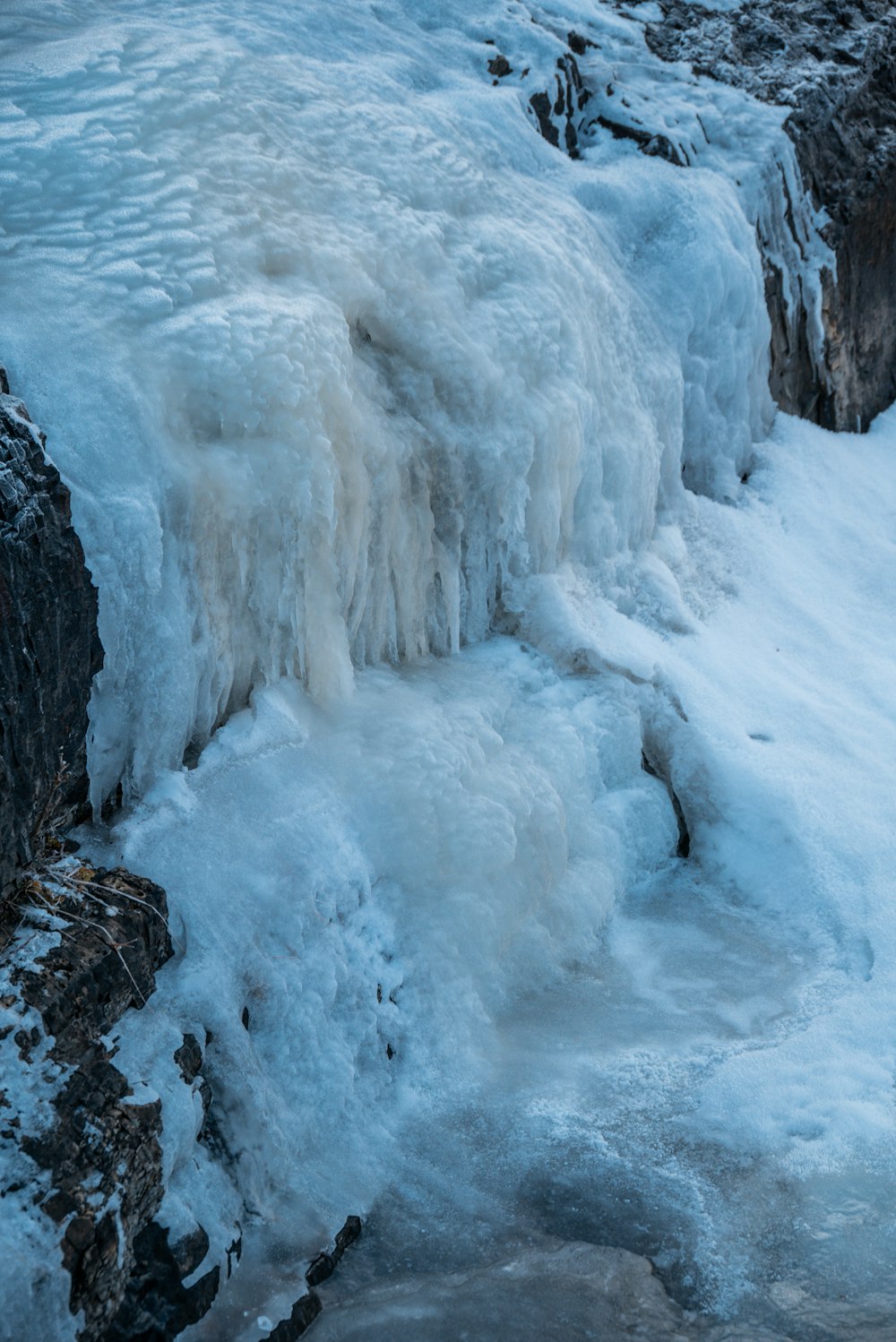 a man standing on a rock next to a frozen waterfall