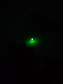Compact flashlight casting a focused beam with neon green glow highlights.