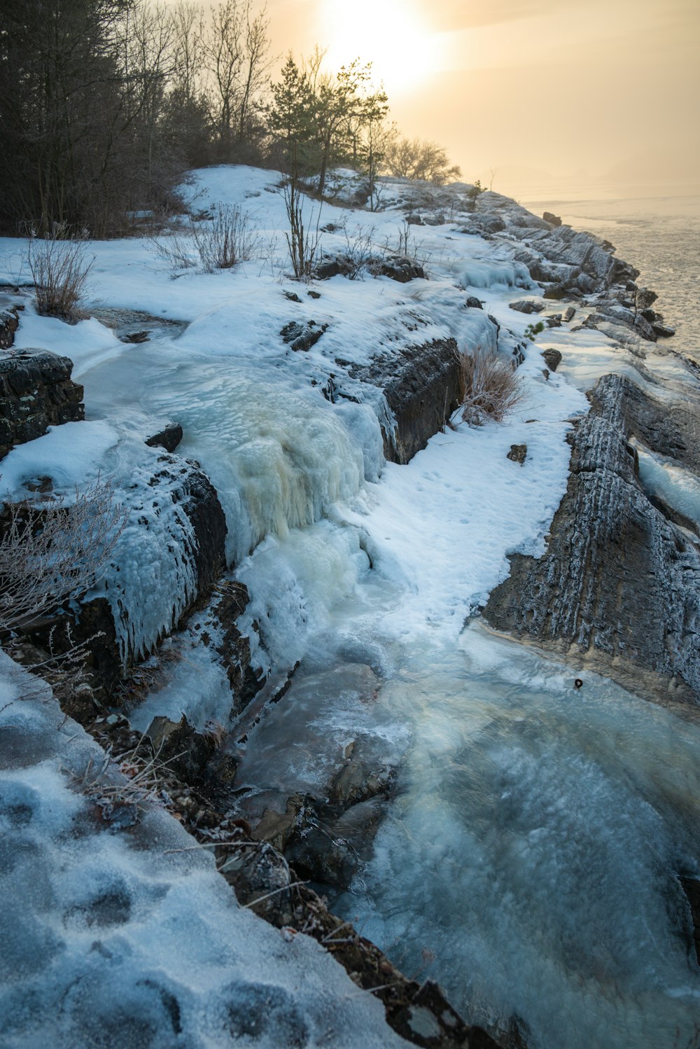 the sun is setting over a frozen river