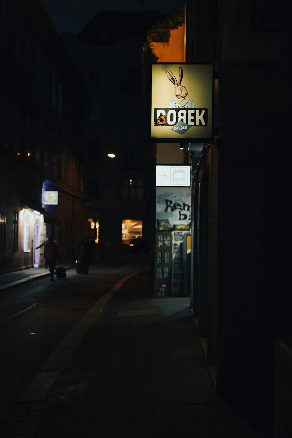 a dark street at night with a store sign lit up