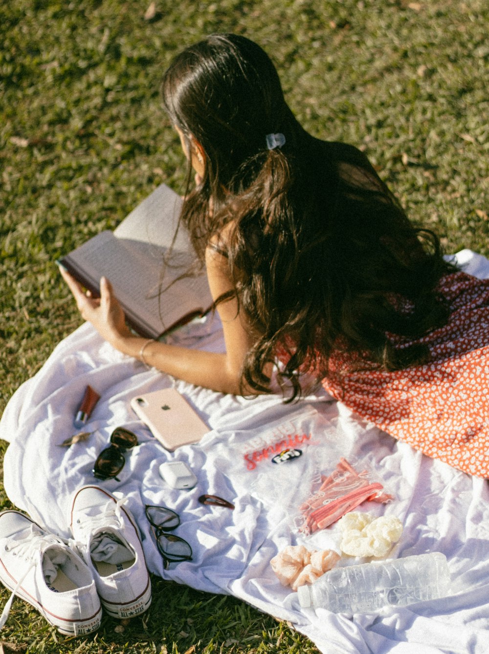 a woman sitting on a blanket reading a book