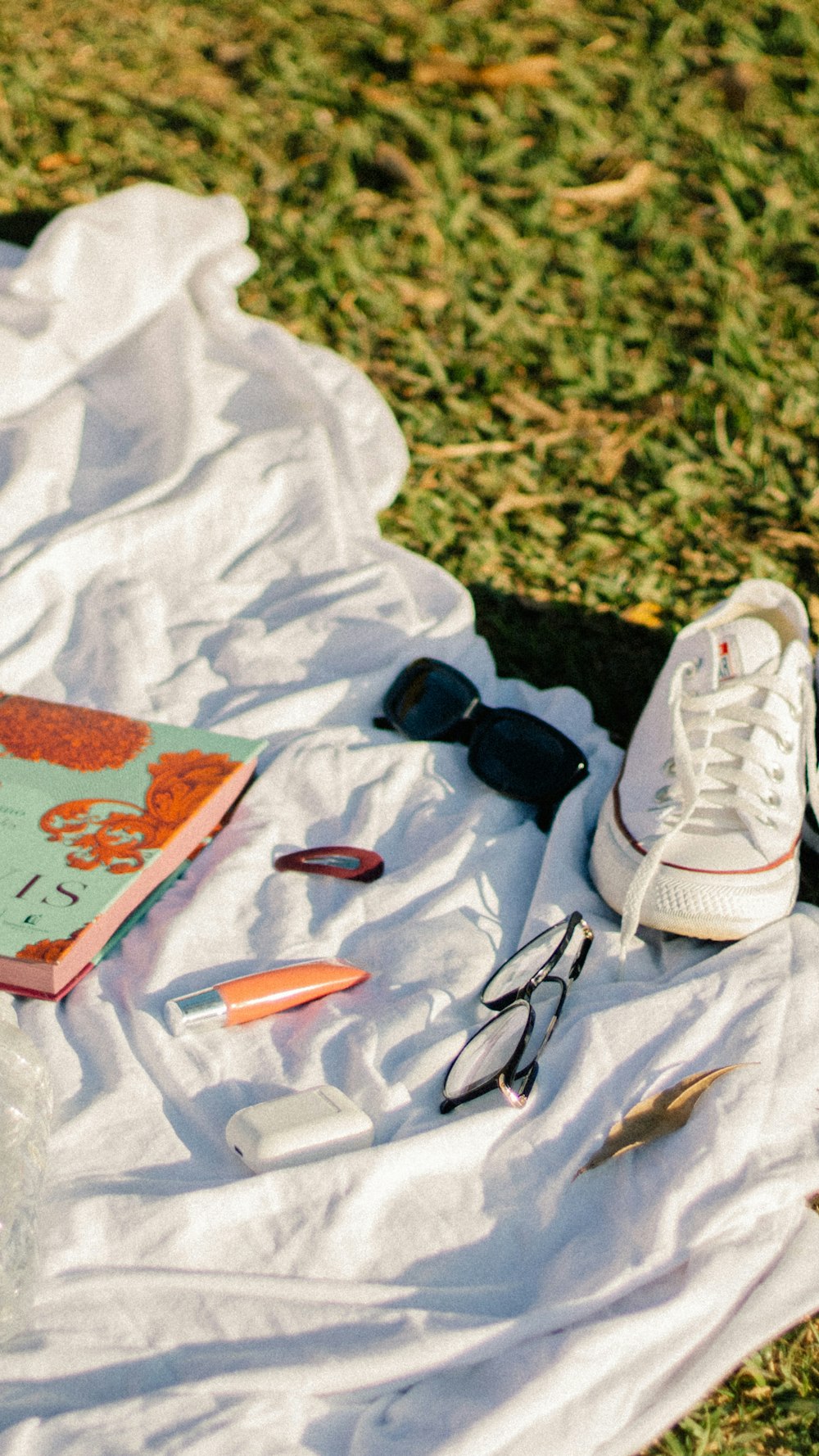 a pair of white sneakers and a book on a blanket