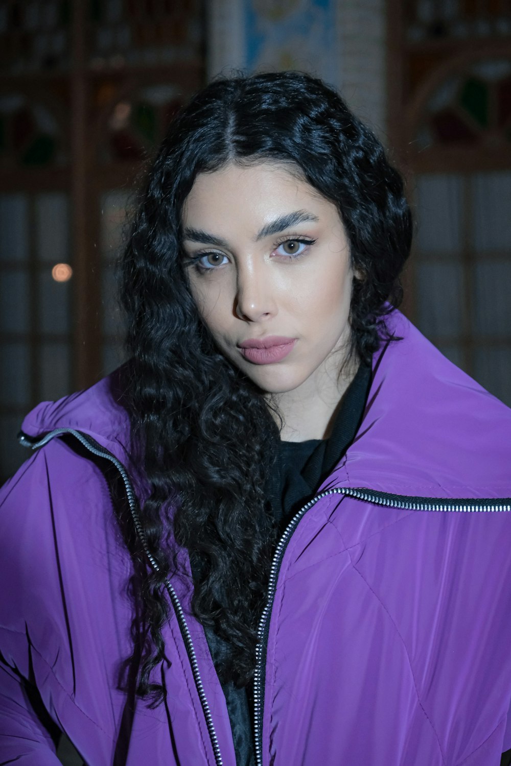a woman with long black hair wearing a purple jacket