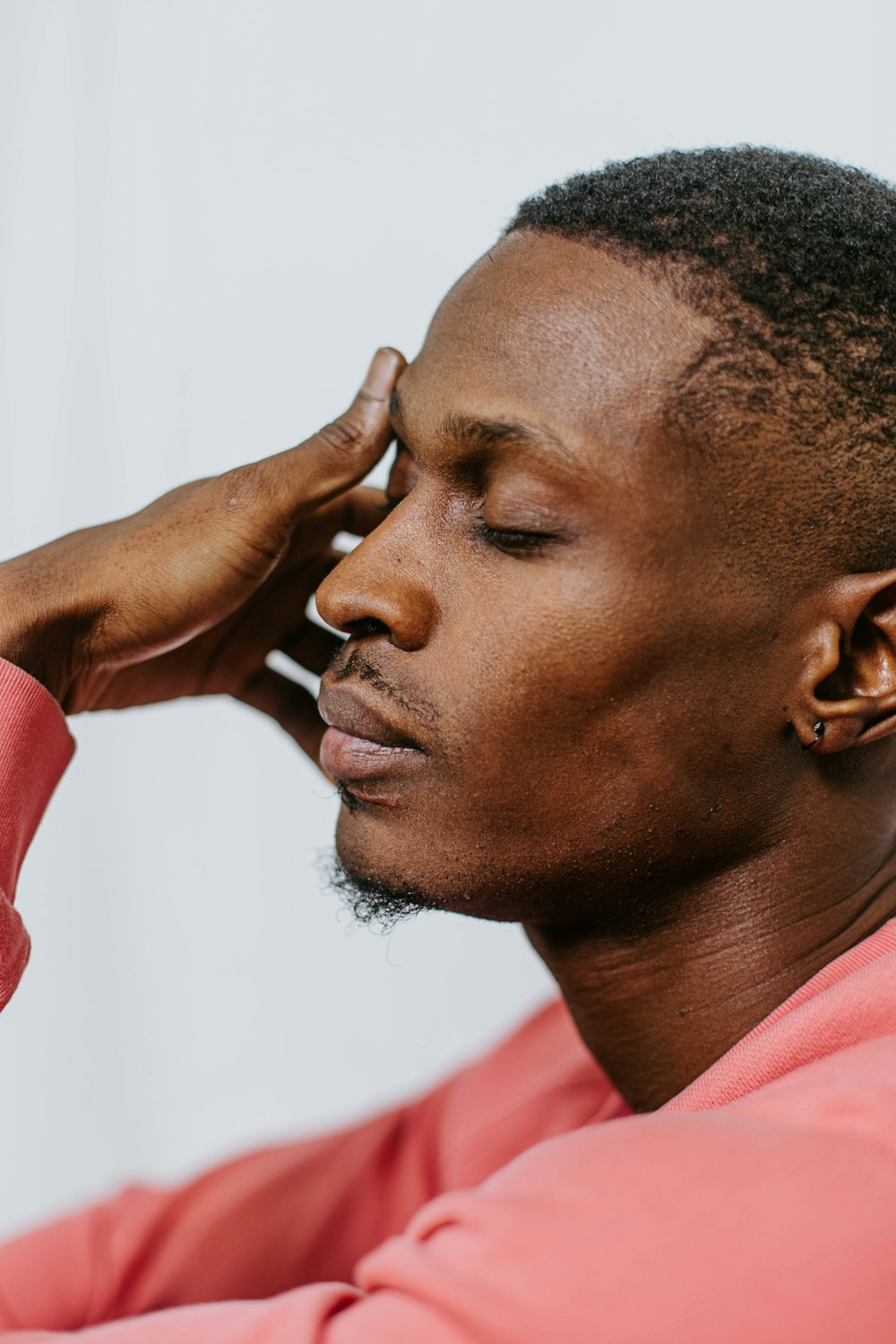 a man in a pink shirt is holding his hand to his head