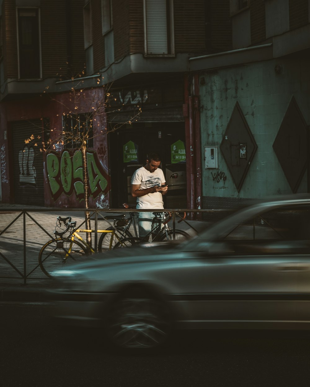 a man standing next to a parked car on a street