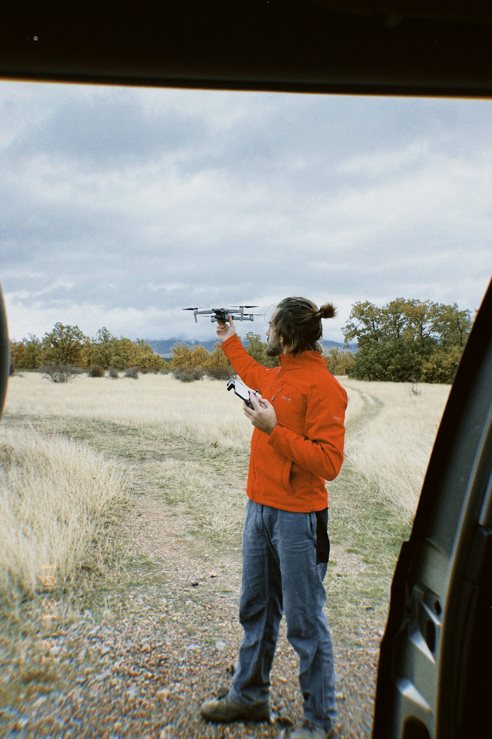 a woman in an orange jacket holding a remote control